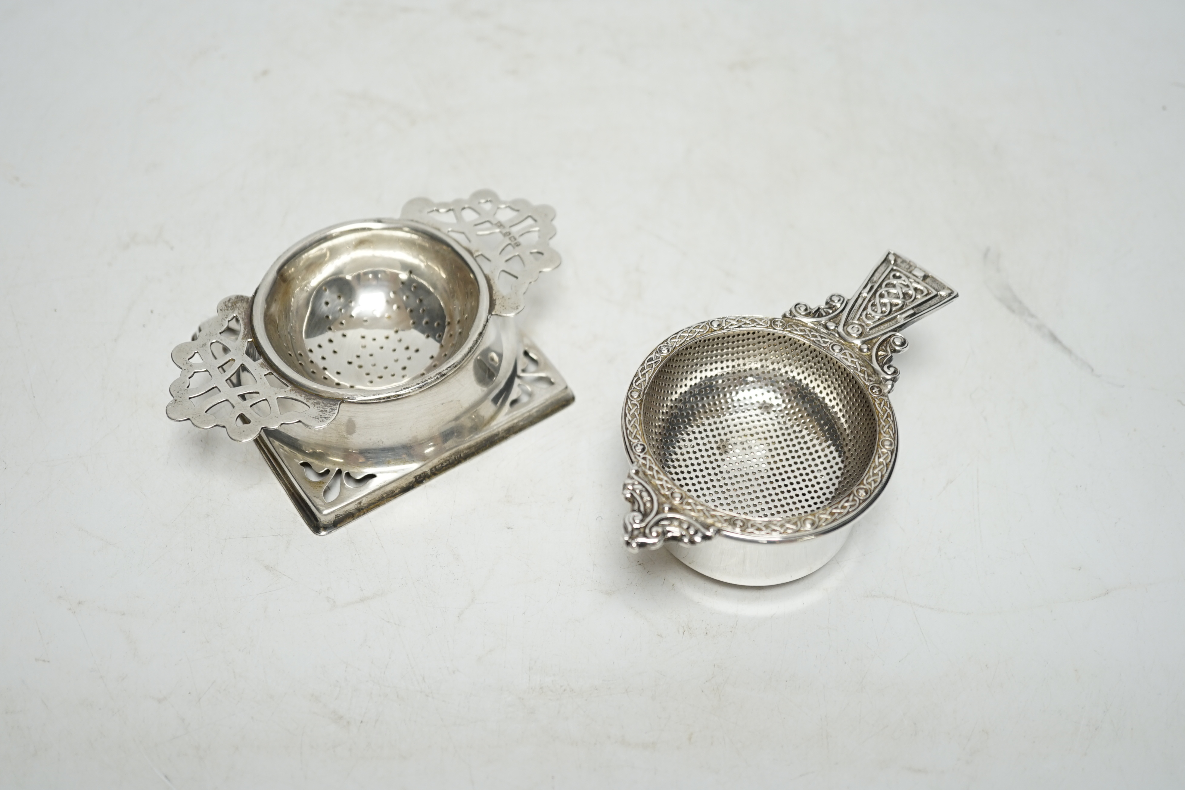 An Elizabeth II silver tea strainer and stand, with Celtic decoration, by Mappin & Webb, Sheffield, 1962, 10.7cm and one other silver tea strainer on stand. Condition - fair